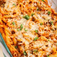 a glass casserole dish filled with pasta and meat, topped with parmesan cheese