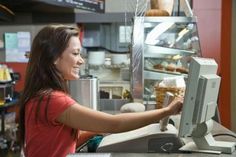 a woman standing in front of a display case filled with donuts