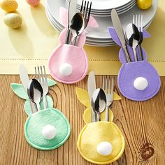 four bunny napkin holders with forks and spoons on a table next to an easter egg