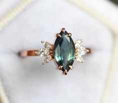 a ring with an oval shaped green stone surrounded by smaller white stones