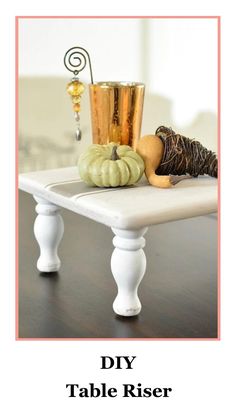 a white table topped with a vase filled with pumpkins next to a candle holder