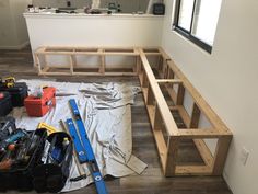 some tools are laying on the floor in front of a window and wooden bench that's being built