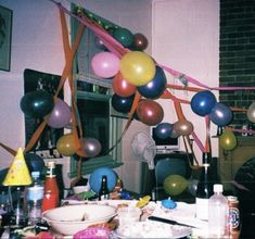 a party with balloons and confetti on the table in front of a fireplace