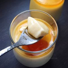 two glasses filled with orange juice and one has a spoon in the cup to scoop it