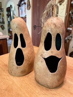 two decorative pumpkins with faces painted on them sitting on a table in a kitchen