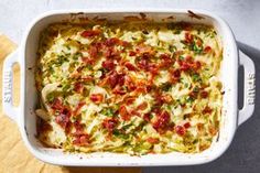 a white casserole dish filled with vegetables and cheese