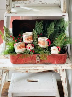 an old white chair with christmas decorations on it and santa mugs in the back