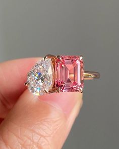 someone is holding an engagement ring with two stones in it and the other side has a pink tourmaline