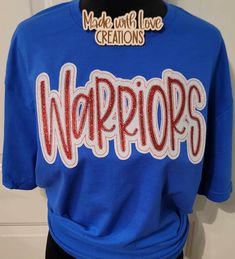 This listing is for a WARRIORS unisex shirt. This embroidered shirt comes in colors/fabric prints of your choice.  THIS LISTING IS ONLY FOR THE MASCOT SHIRT PICTURED AND LISTED ABOVE  OTHER MASCOTS ARE AVAILABLE PLEASE MESSAGE US OR BROWS OUR SHOP. IF THIS SHIRT IS ORDERED AND YOU PUT ANOTHER MASCOT NAME IT WILL BE CANCELLED. Feel free to request color changes. If you have no special requests, your design will resemble the first picture in the listing as closely as possible. Some fabrics in the applique design may differ slightly depending on availability of fabric. We use a mix of HTV glitter or glitter fabric and sequins on our designs.  We use unisex Gildan brand sweatshirts, Gildan softstyle t-shirt and Gildan long sleeve shirt for most orders we also use other brands when needed.  We College Red Tops With Embroidered Text, Red College Tops With Embroidered Text, Red College Top With Embroidered Text, Red Embroidered Text College Tops, Team-colored Tops With Embroidered Graphics For Fans, Team-colored Cotton Tops With Embroidered Graphics, Blue Embroidered College T-shirt, Embroidered School Spirit Tops For Game Day, School Spirit Embroidered Tops For Game Day