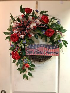 a wreath with red, white and blue flowers hanging on the front door for memorial day