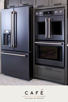 two stainless steel ovens side by side in a kitchen with gray cabinets and white tile flooring