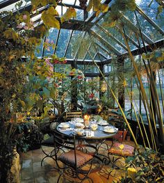 an outdoor dining area with tables and chairs, surrounded by greenery in the background