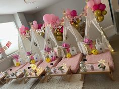 a room filled with lots of pink and gold balloons in the shape of teepees