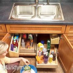 a woman kneeling down in front of a kitchen sink filled with dishes and condiments