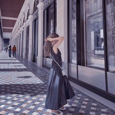 a woman standing in front of a store window with her hand on her head and looking at the windows