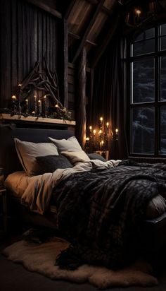 a bed with blankets and pillows in a room next to a window filled with candles