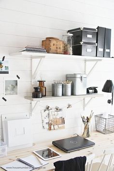 a white desk topped with lots of shelves filled with boxes and containers next to a laptop computer