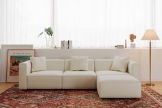 a white couch sitting on top of a wooden floor next to a lamp and window