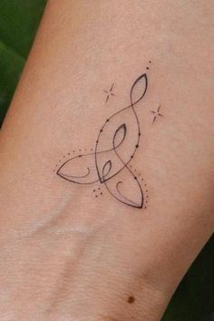 a woman's wrist with a musical note tattoo on the left side of her arm