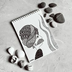 a spiral notebook sitting on top of a table next to rocks and seashells