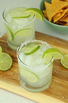 two margaritas on a cutting board with chips