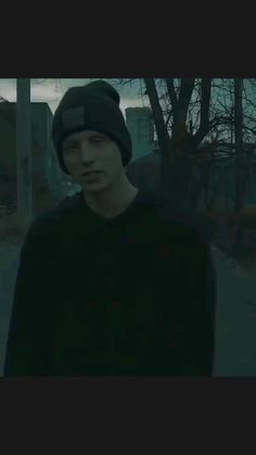 a young man wearing a beanie standing in the dark