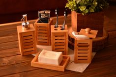 a wooden table topped with soaps and toothbrushes next to a potted plant