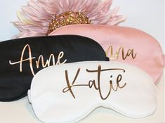 three sleep masks with name on them sitting next to a pink and white flower in the corner