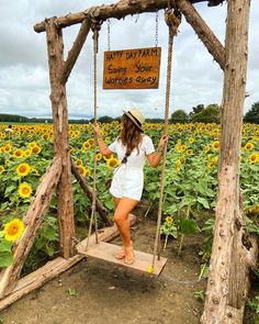 a woman on a swing in the middle of a sunflower field with a sign that says happy day farm