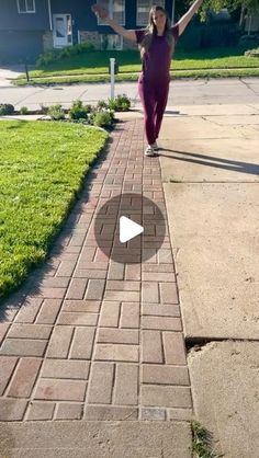 a woman walking down a sidewalk with her arms in the air