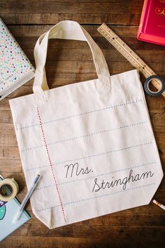 a tote bag sitting on top of a wooden table next to scissors and tape