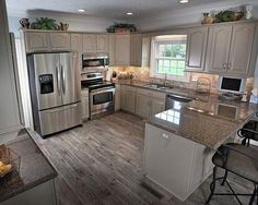 a large kitchen with stainless steel appliances and wood flooring is pictured in this image