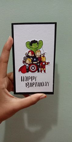 a hand holding up a birthday card with an image of the avengers