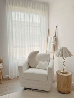 a white chair sitting in front of a window next to a lamp