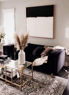 a living room filled with furniture and a large painting on the wall above it's coffee table