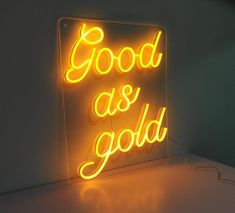 a neon sign that says good as gold on the side of a white counter top