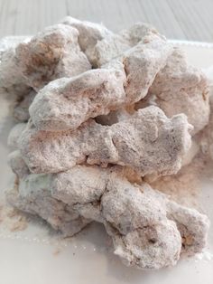 a pile of powdered donuts sitting on top of a white plate