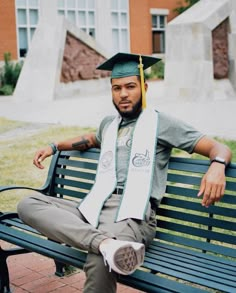 a man sitting on top of a green bench wearing a graduation cap and tassel