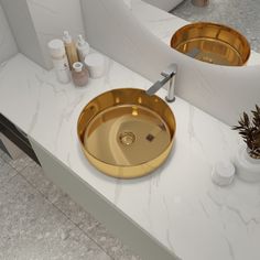 two gold sinks in a bathroom with marble counter tops