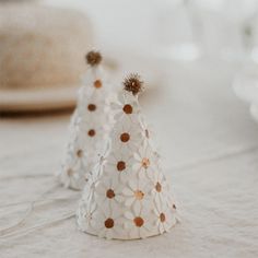 two small white paper hats sitting on top of a table next to plates and glasses