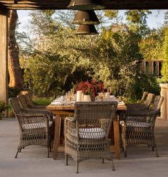 an outdoor dining table with chairs and a bell hanging from the ceiling