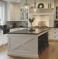 a large kitchen with white cabinets and black counter tops, an island in the middle