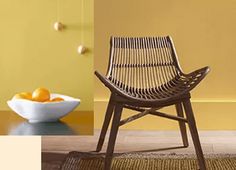 a chair sitting on top of a wooden floor next to a bowl of oranges