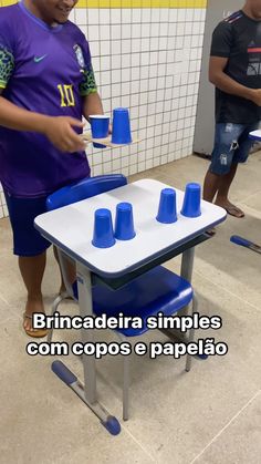 a young man standing in front of a table with blue cups on top of it