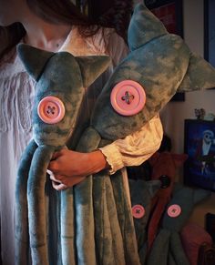 a person holding two stuffed animals in their arms with buttons on them's eyes