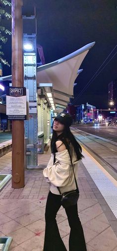 a woman standing next to a train station at night