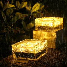 two square lights sitting on top of a black table covered in water and raindrops