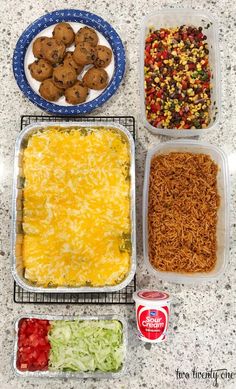 four containers filled with food sitting on top of a counter next to cans of soda