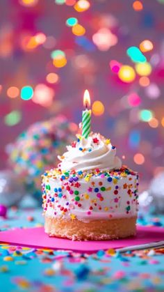 a birthday cupcake with white frosting and sprinkles on a pink napkin