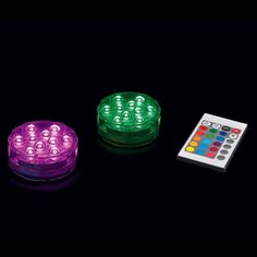 three different colored lights sitting next to each other on a black surface with a remote control